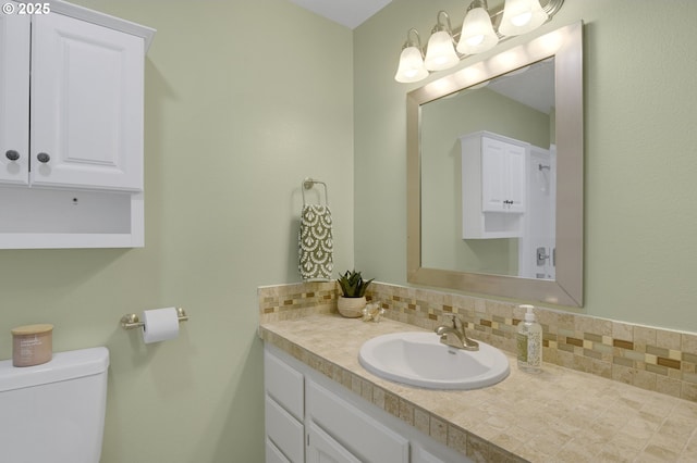 half bath with toilet, tasteful backsplash, and vanity
