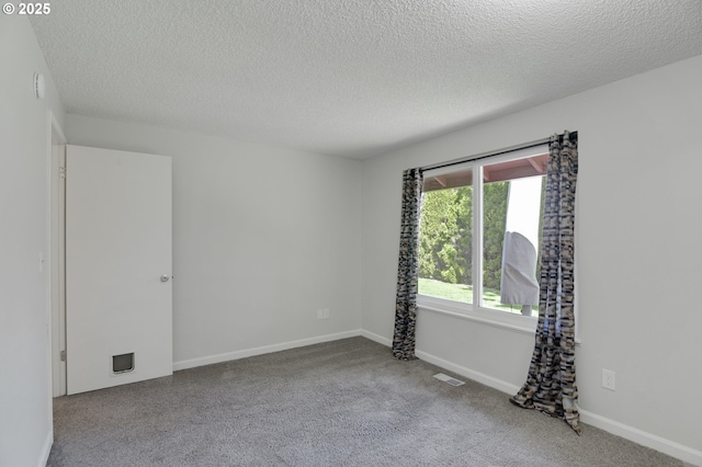 unfurnished room featuring baseboards, carpet flooring, a textured ceiling, and visible vents