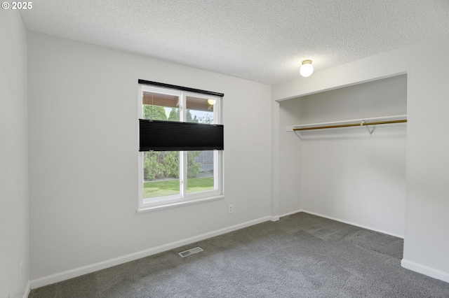 unfurnished bedroom featuring multiple windows, carpet, a textured ceiling, and visible vents