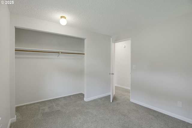 unfurnished bedroom featuring carpet floors, baseboards, a closet, and a textured ceiling
