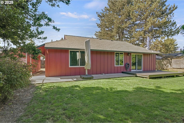 back of property featuring board and batten siding, a deck, fence, a yard, and a shingled roof