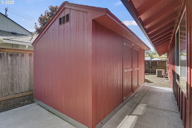 view of shed with fence and cooling unit