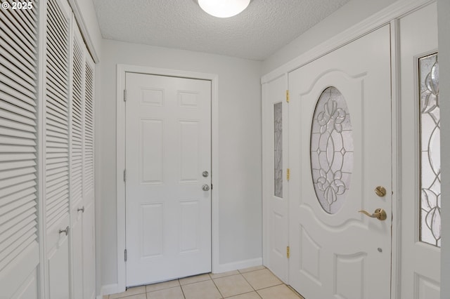 foyer featuring light tile patterned floors, baseboards, and a textured ceiling