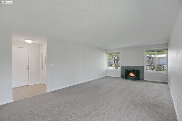 unfurnished living room featuring tile patterned flooring, a fireplace with flush hearth, baseboards, a textured ceiling, and carpet flooring