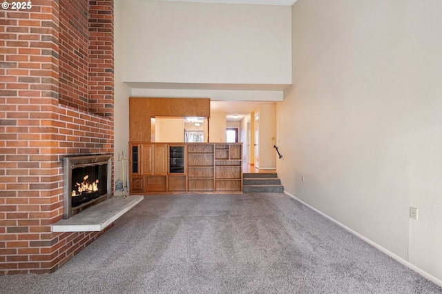1200 NE Territorial Rd Unit 83, Canby, OR 97013 - unfurnished living room featuring carpet floors, a brick fireplace, a towering ceiling, and baseboards