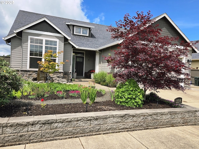 craftsman-style house featuring roof with shingles and stone siding