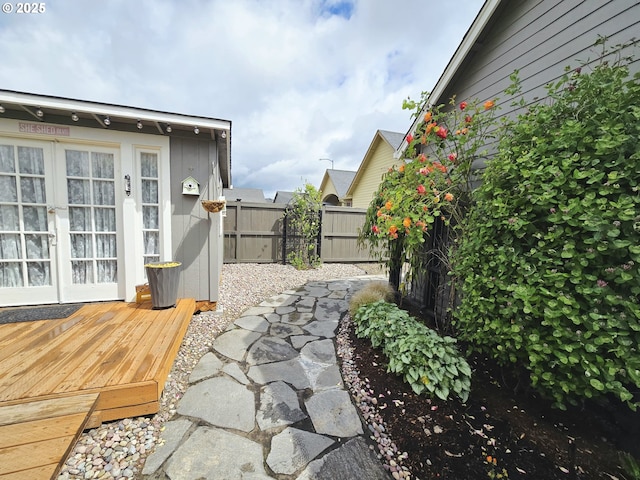 view of yard featuring fence, french doors, and a deck