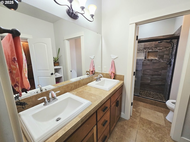 bathroom featuring a shower stall, toilet, double vanity, and a chandelier