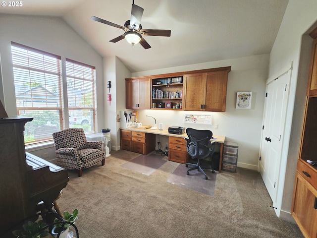 office area with lofted ceiling, light colored carpet, a ceiling fan, baseboards, and built in study area
