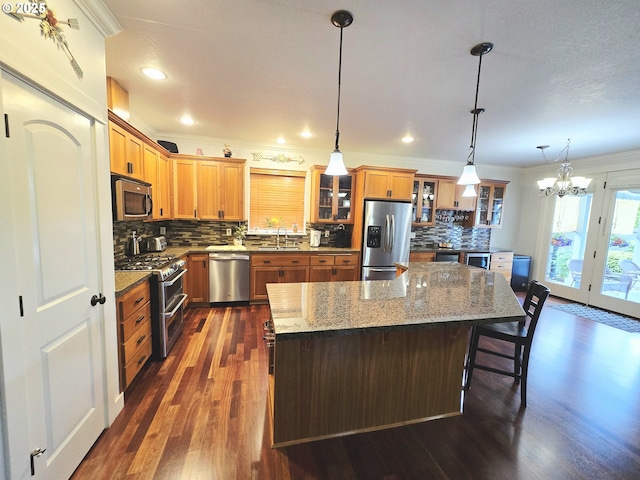 kitchen featuring appliances with stainless steel finishes, a sink, ornamental molding, a chandelier, and tasteful backsplash