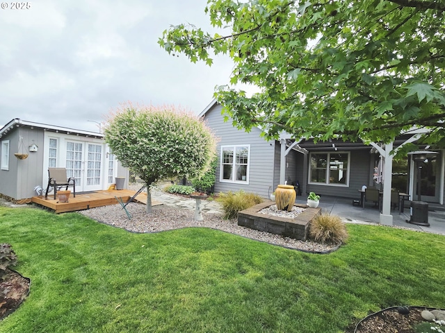 back of property featuring a wooden deck, a yard, and a patio