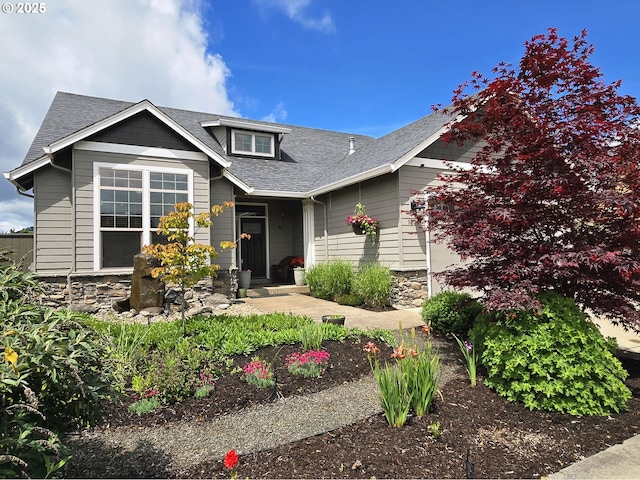 view of front of property featuring stone siding, a shingled roof, and a garage