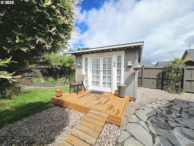 wooden terrace featuring a fenced backyard, french doors, and an outbuilding