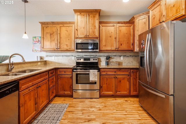 kitchen featuring appliances with stainless steel finishes, tasteful backsplash, sink, hanging light fixtures, and light stone countertops