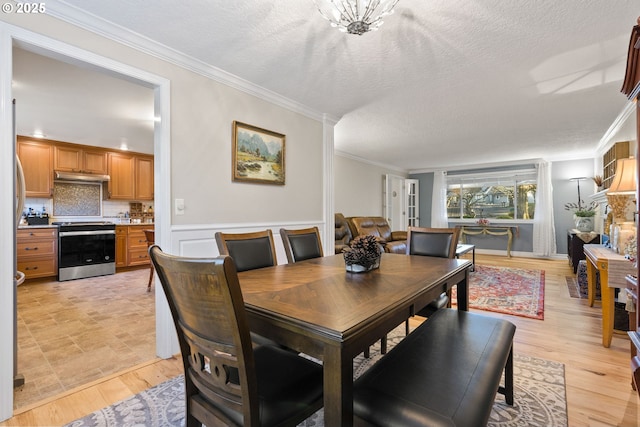 dining space with a textured ceiling, ornamental molding, and a notable chandelier