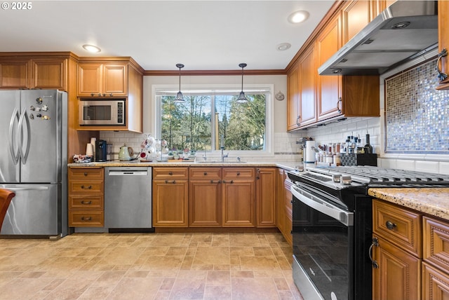 kitchen featuring appliances with stainless steel finishes, wall chimney exhaust hood, tasteful backsplash, light stone countertops, and ornamental molding