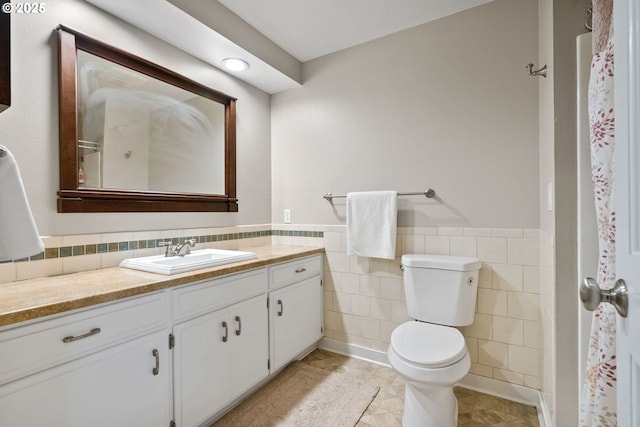 bathroom featuring tile walls, toilet, and vanity