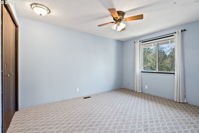 carpeted spare room with a textured ceiling and ceiling fan