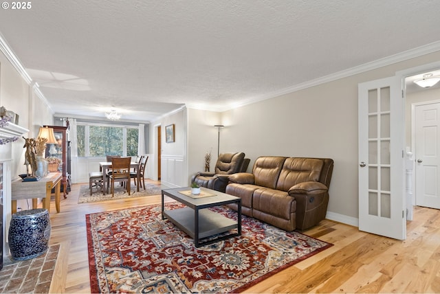 living room with light wood-type flooring, a textured ceiling, and ornamental molding