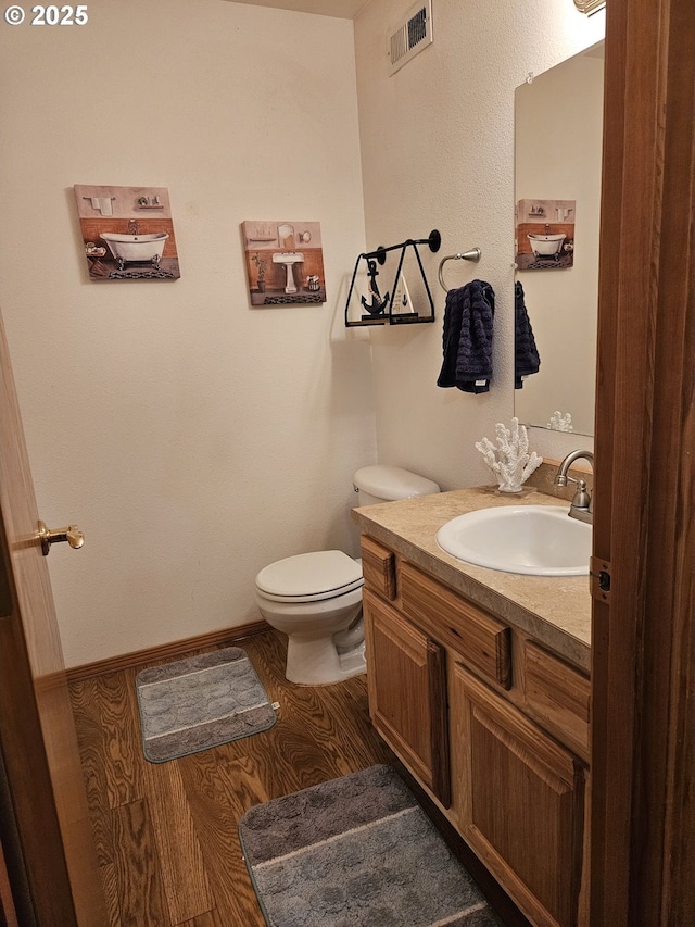 510 NE Yamhill St, Sheridan, OR 97378 - half bathroom featuring toilet, vanity, wood finished floors, and visible vents