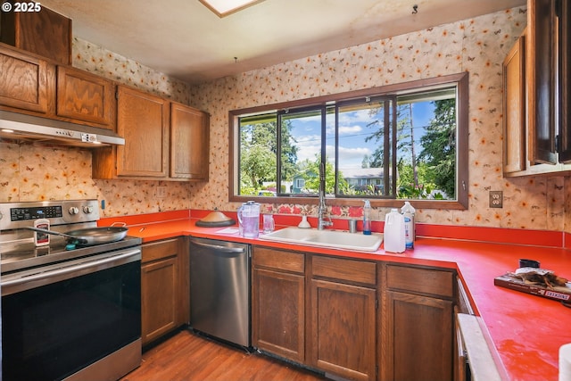 6395 SW 190th Ave, Beaverton, OR 97078 - kitchen featuring appliances with stainless steel finishes, under cabinet range hood, wallpapered walls, a sink, and light wood-style flooring