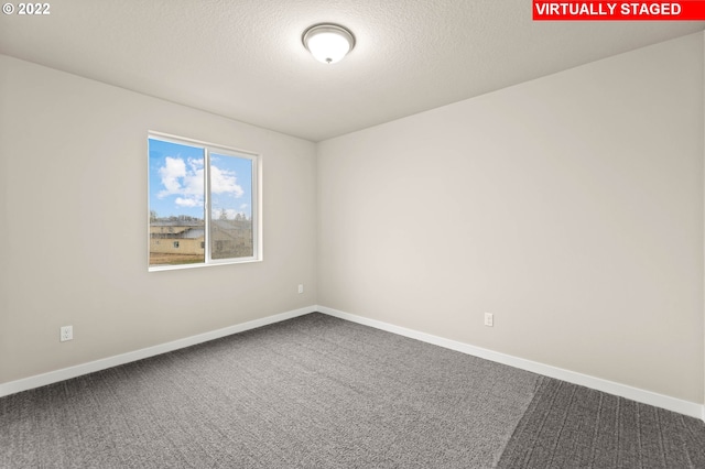 carpeted empty room featuring a textured ceiling