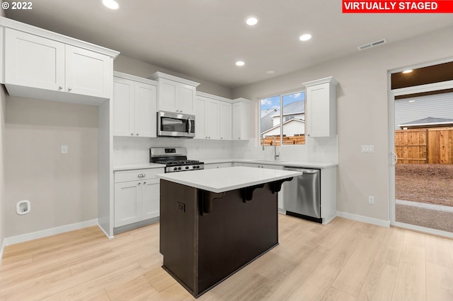 kitchen featuring sink, stainless steel appliances, a kitchen island, light hardwood / wood-style flooring, and white cabinets