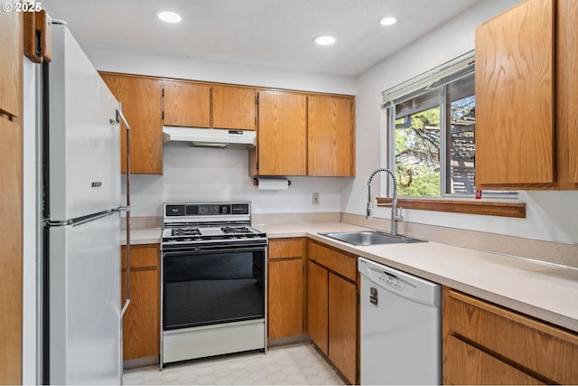 kitchen featuring recessed lighting, under cabinet range hood, white appliances, a sink, and light countertops