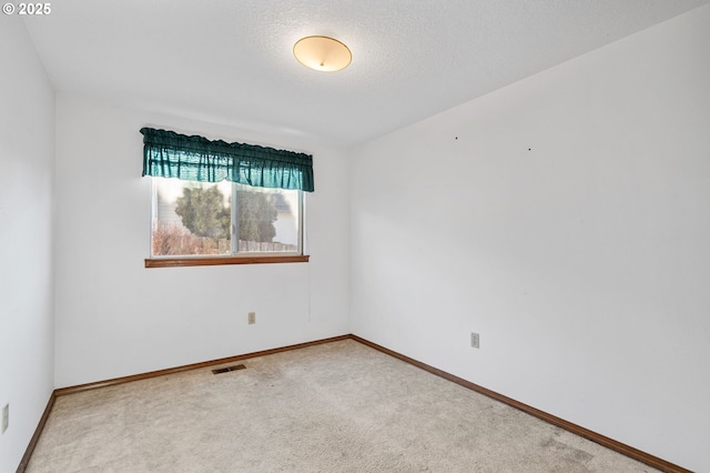 carpeted empty room featuring a textured ceiling, visible vents, and baseboards