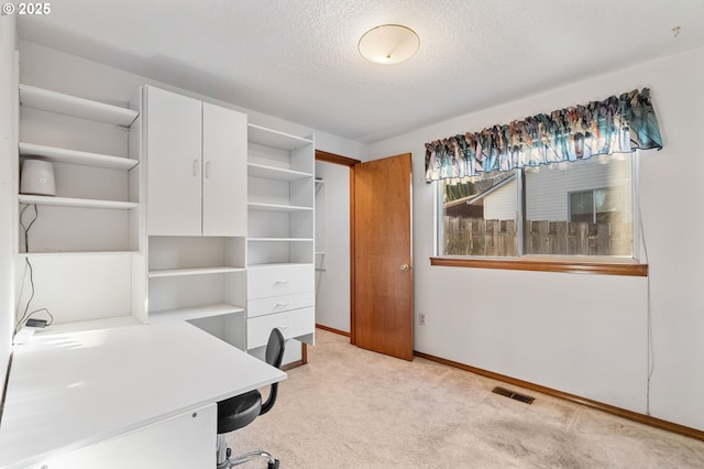 unfurnished office with light carpet, baseboards, visible vents, and a textured ceiling