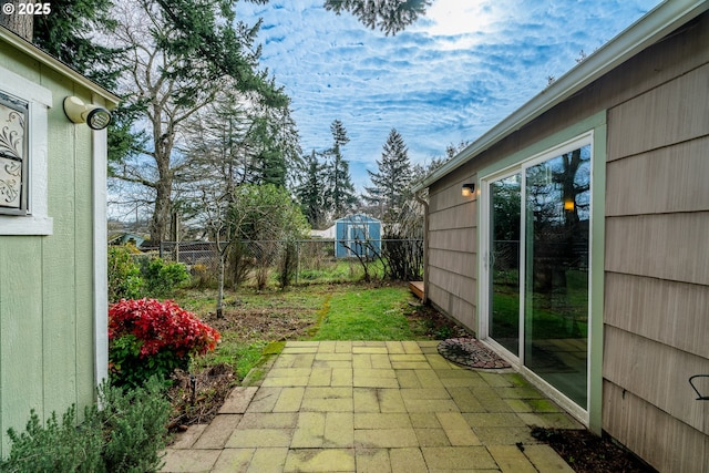 view of patio / terrace with a shed, fence, and an outbuilding