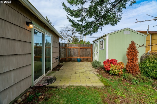 view of yard featuring an outbuilding, a patio area, fence, and a shed