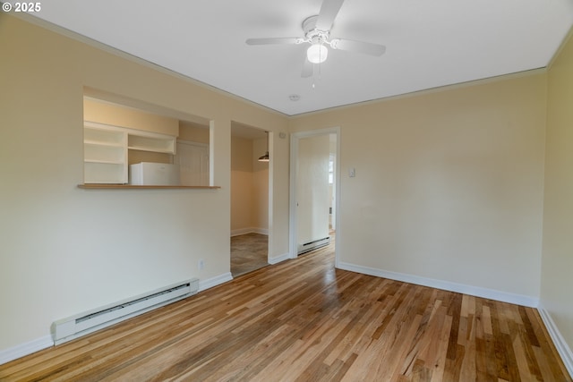 empty room featuring baseboard heating, wood finished floors, and baseboards