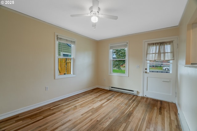 spare room with light wood finished floors, baseboard heating, a ceiling fan, ornamental molding, and baseboards