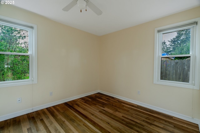 unfurnished room with a ceiling fan, dark wood finished floors, and baseboards