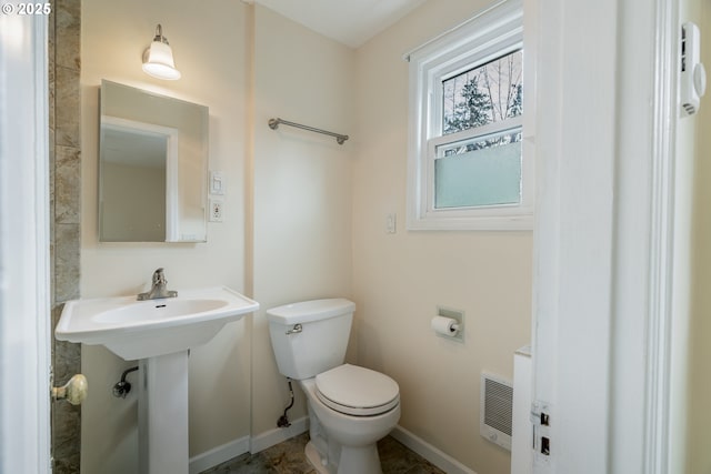 bathroom with toilet, heating unit, and baseboards