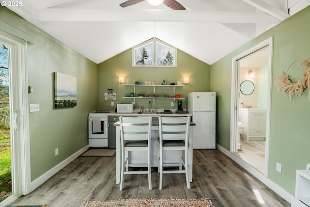 kitchen featuring vaulted ceiling, white appliances, a sink, and wood finished floors