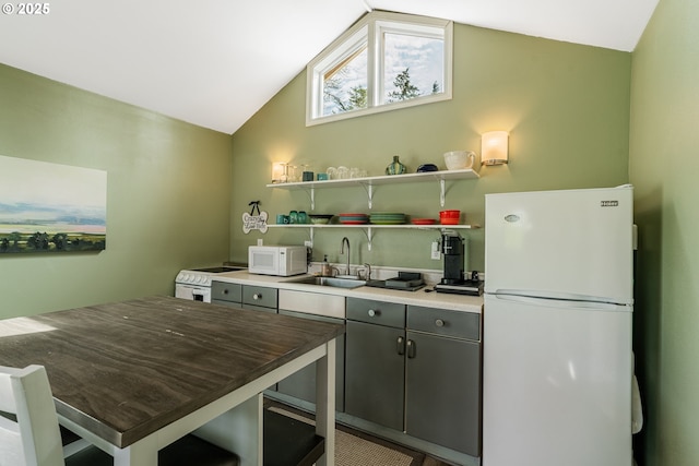 kitchen featuring vaulted ceiling, white appliances, and a sink