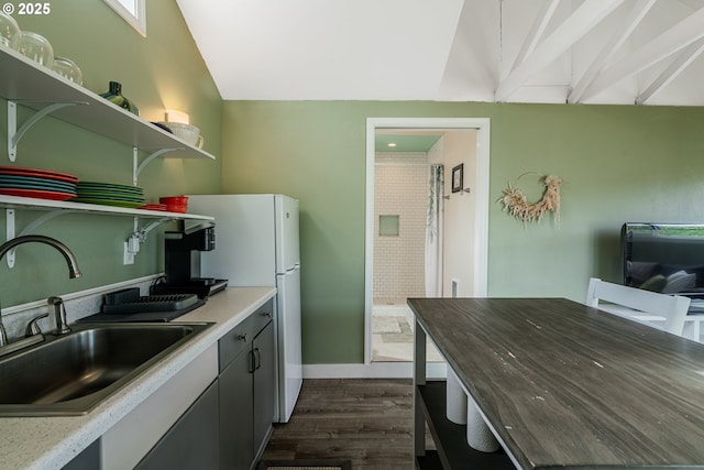 kitchen with dark wood finished floors, open shelves, freestanding refrigerator, vaulted ceiling, and a sink