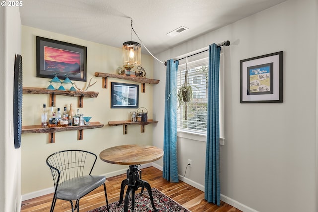 dining area with baseboards, visible vents, and wood finished floors