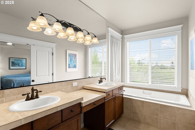 bathroom with a sink, a relaxing tiled tub, double vanity, and connected bathroom