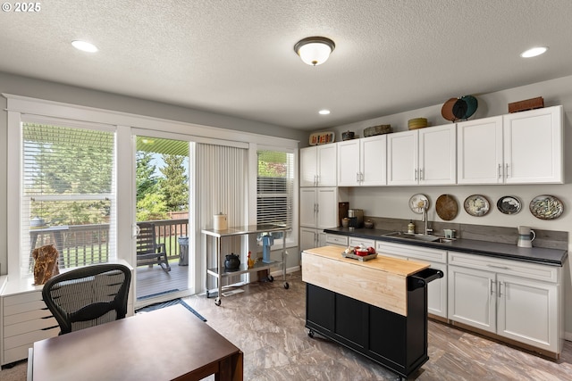 kitchen with wood counters, white cabinets, recessed lighting, and a textured ceiling