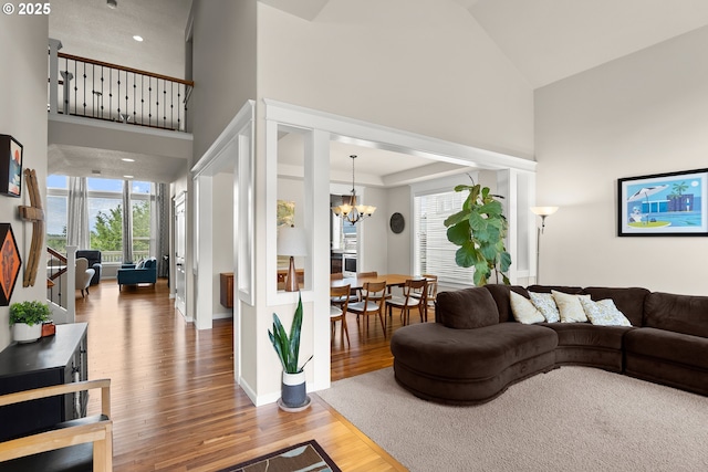 living area featuring high vaulted ceiling, a chandelier, and light wood-type flooring