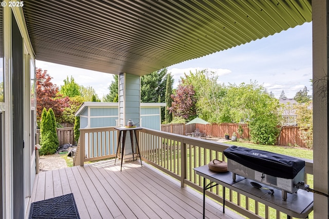 wooden terrace featuring a fenced backyard, an outdoor structure, and grilling area