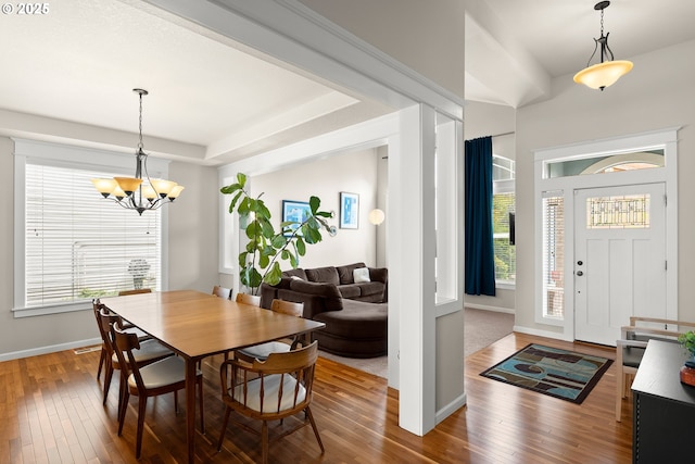 dining space with baseboards, a chandelier, hardwood / wood-style flooring, and a healthy amount of sunlight