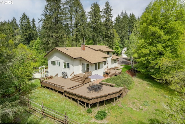 back of house with roof with shingles, fence, a deck, a chimney, and a lawn