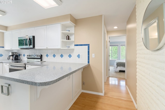 kitchen with light wood-style flooring, a breakfast bar area, white cabinetry, and stainless steel appliances