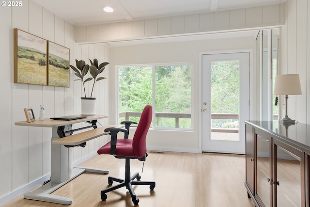 office space featuring baseboards, wood finished floors, a healthy amount of sunlight, and visible vents