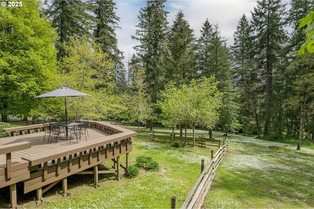 surrounding community with a lawn, a deck, fence, and outdoor dining space