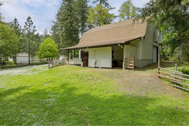rear view of property with roof with shingles, an outbuilding, and an exterior structure